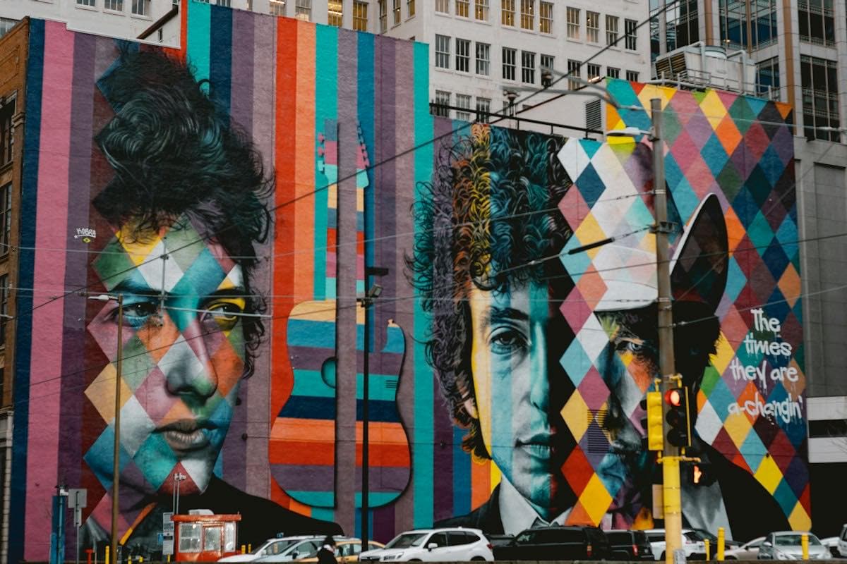 Two people in front of a colorful mural