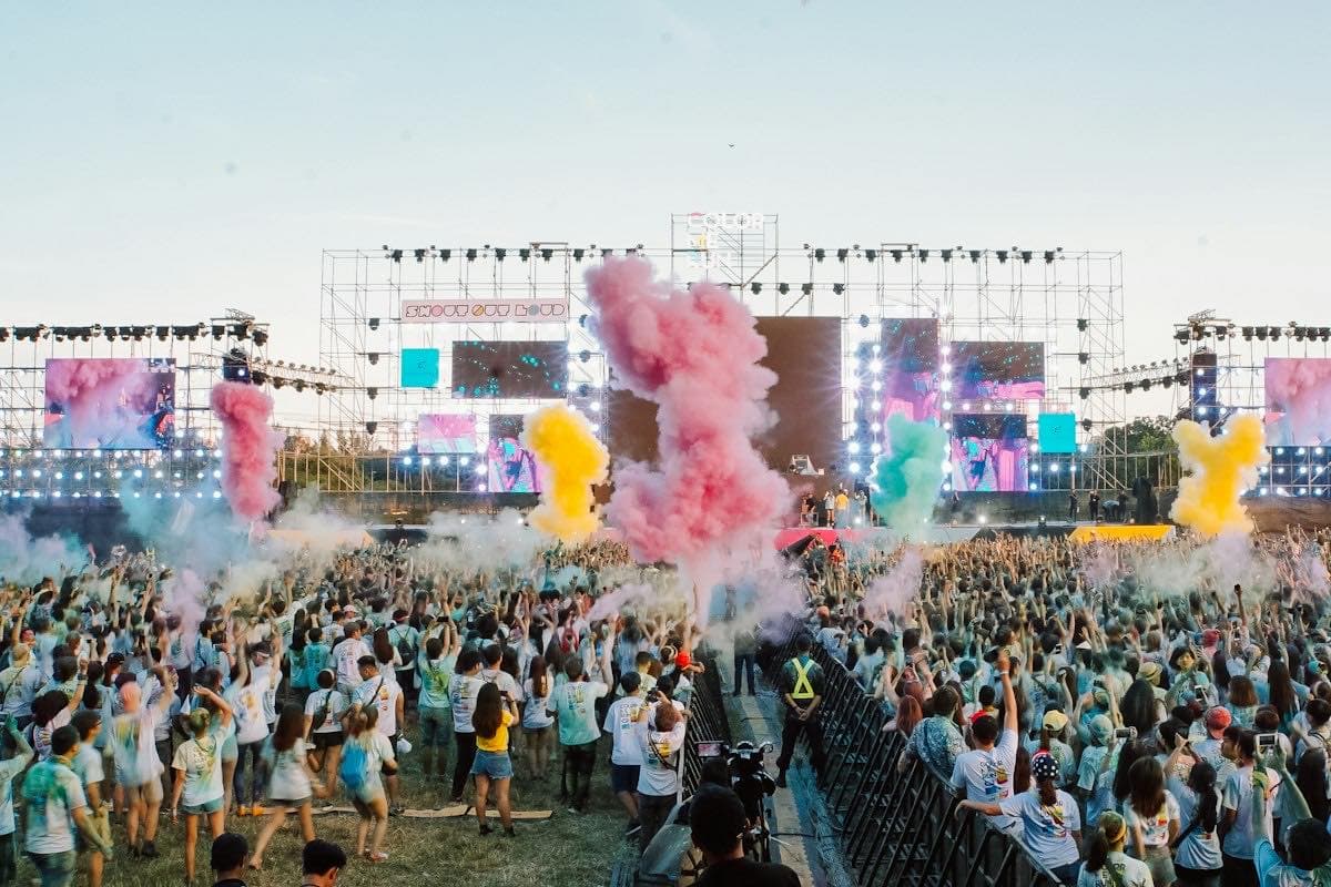 A crowd on a green field at a daytime festival