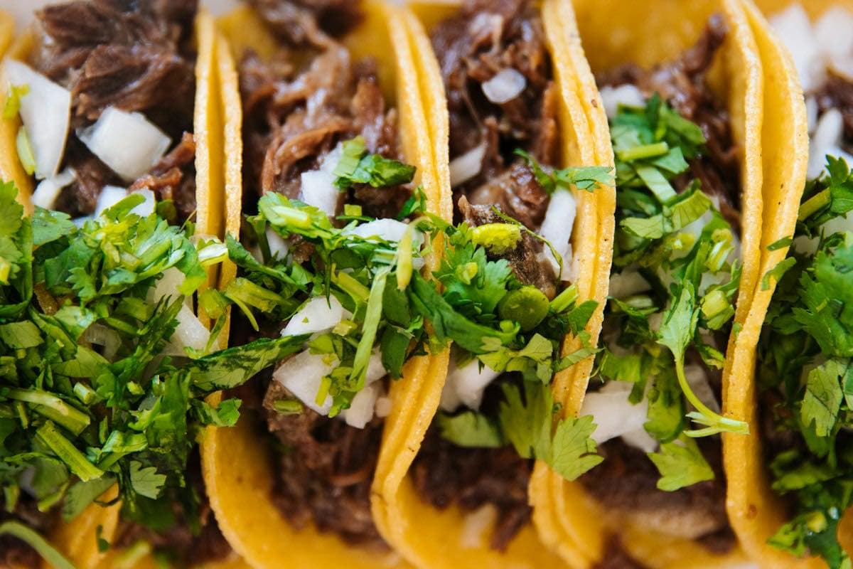Three street tacos with onion and cilantro