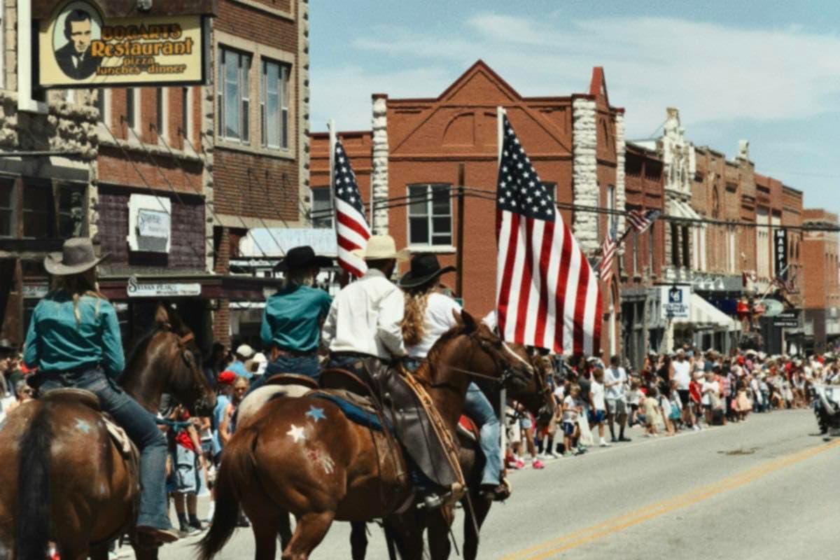 Riders on horseback in a parade down a flag-lined street