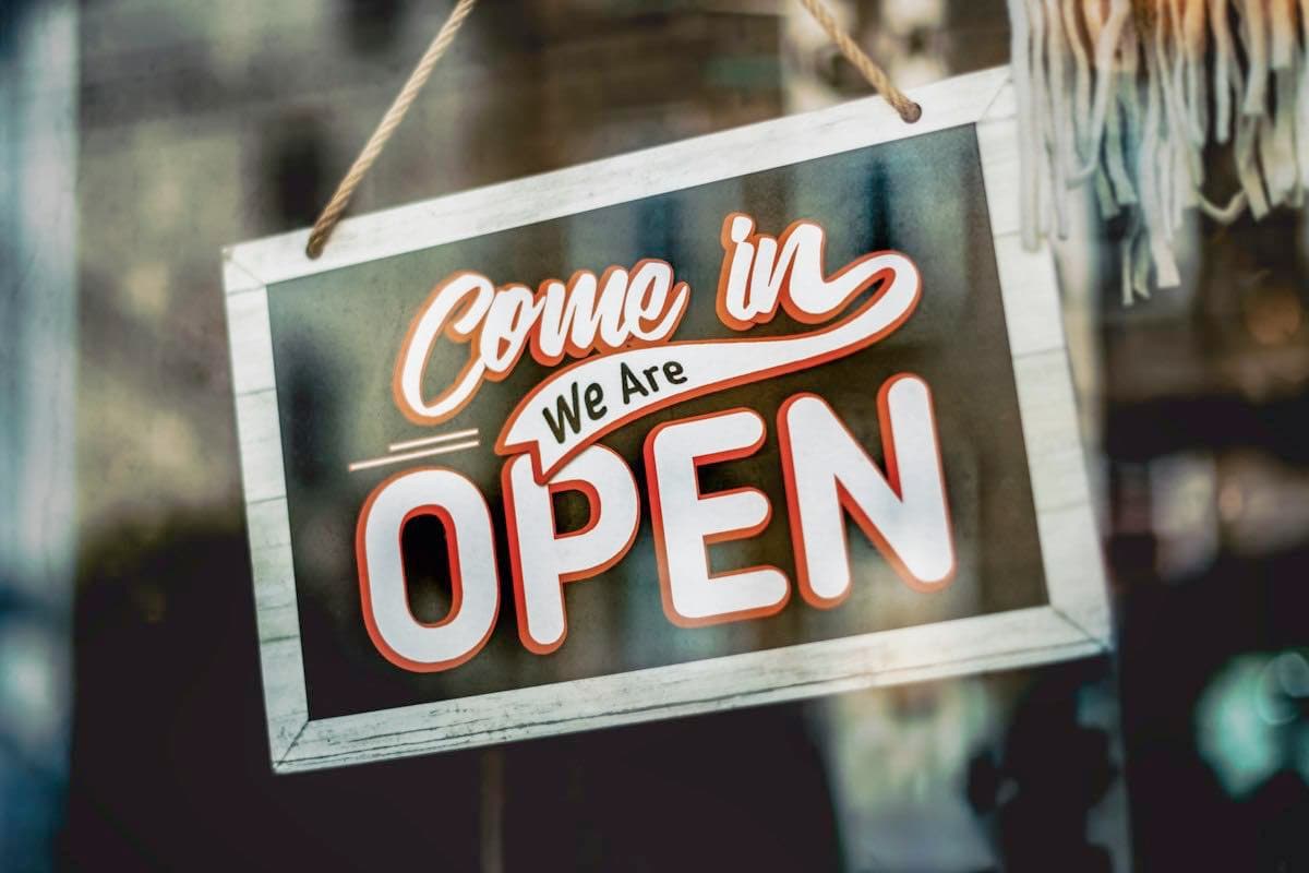 A come in, we are open sign in a shop window