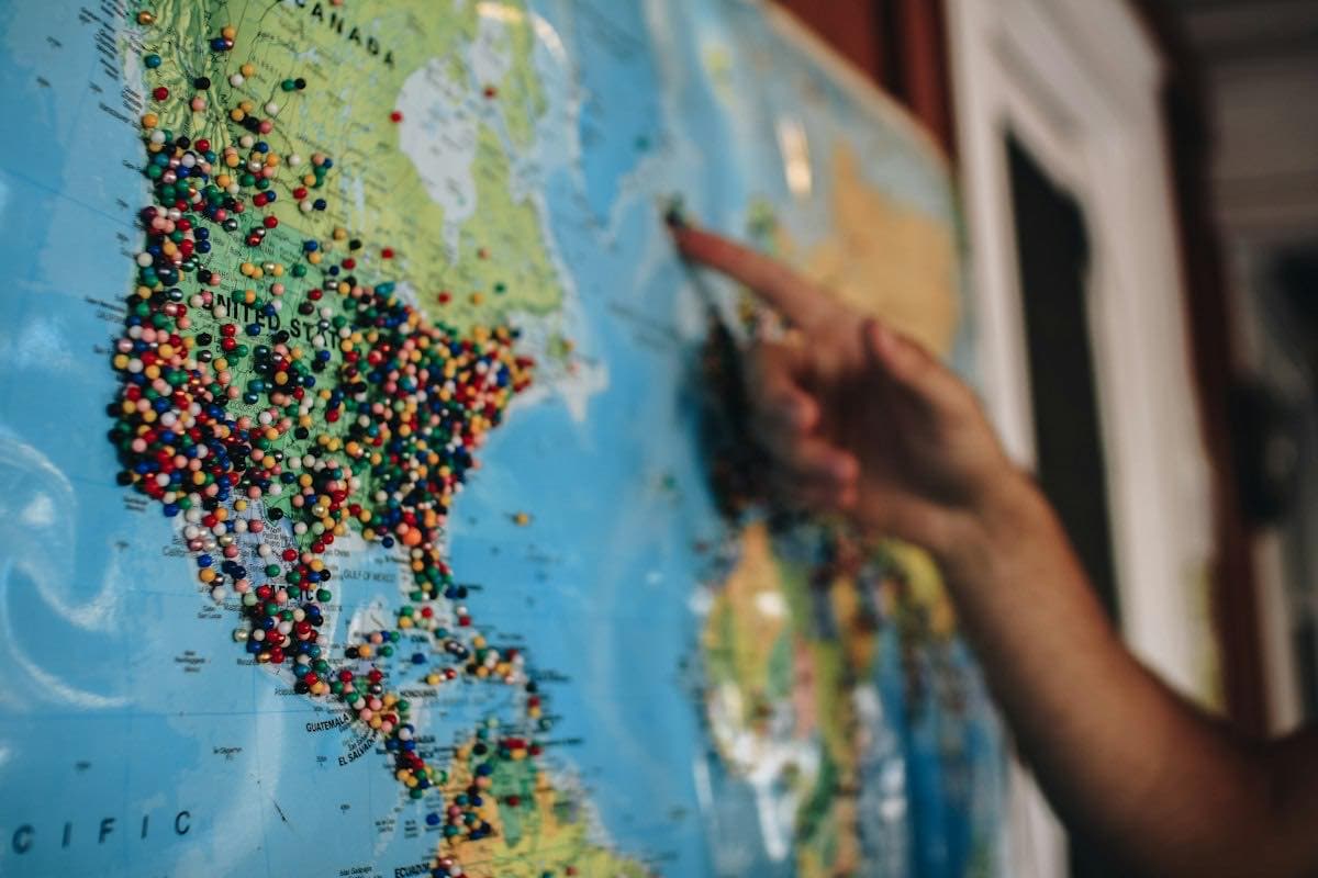 A person pointing at a map covered in pins