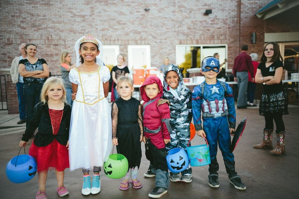 Kids in costume holding a jack-o-lantern on Halloween