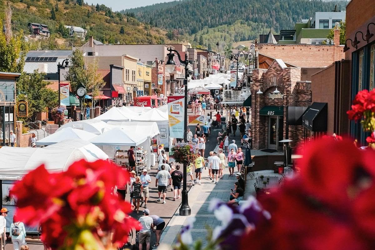 People walking past shops and market tents downtown